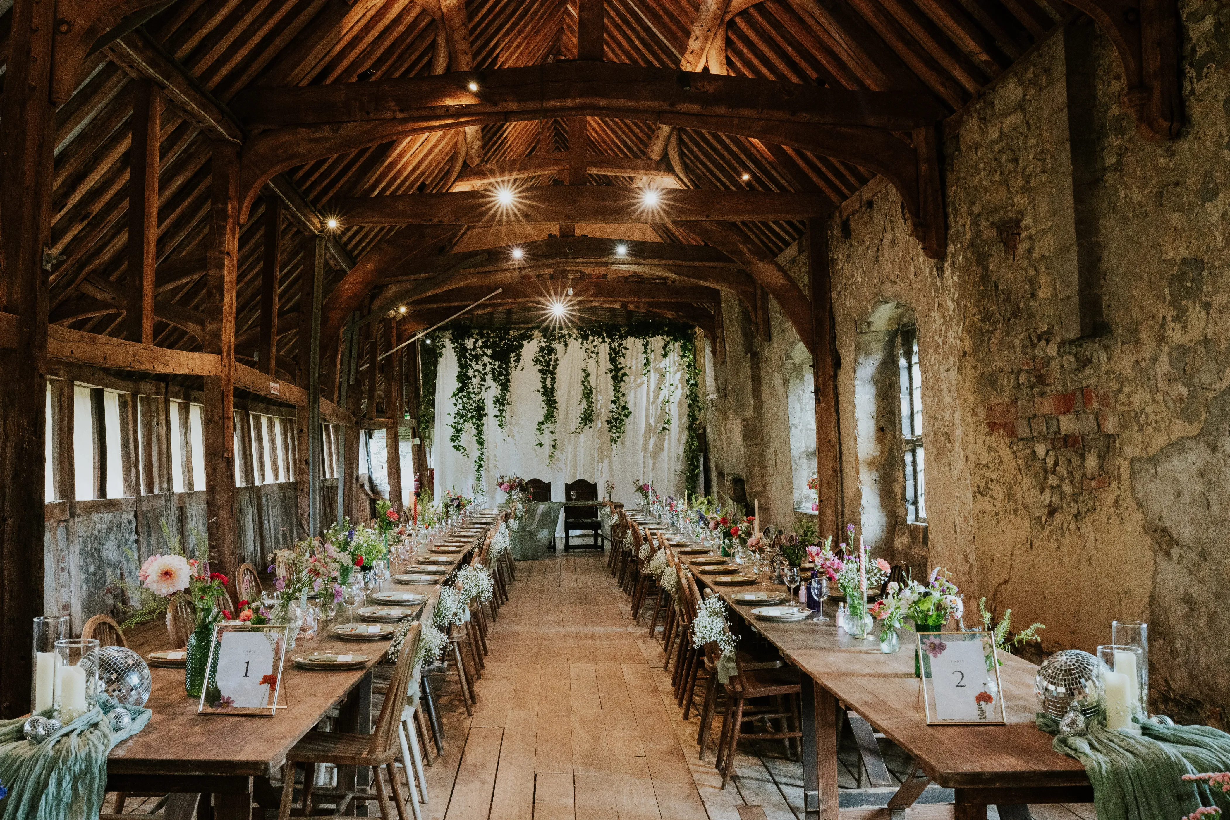 Rustic barn wedding reception long tables ivy backdrop